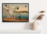 A framed wall art print hangs on a white wall above a white mantel, styled with a beige ceramic vase holding dried pampas grass. The artwork depicts a surreal coastal scene with a giant slug-like creature, a seated person, blue water, and a hot air balloon.