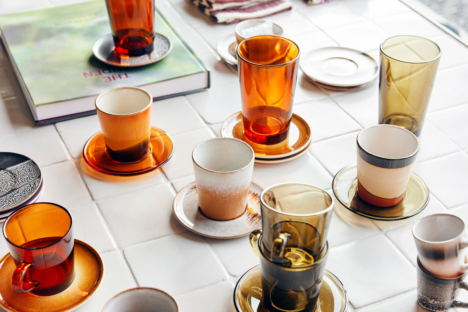 Collection of colorful coffee cups and saucers on a tiled surface.