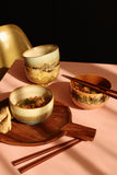 Three ceramic bowls with food on a pink surface with wooden chopsticks.