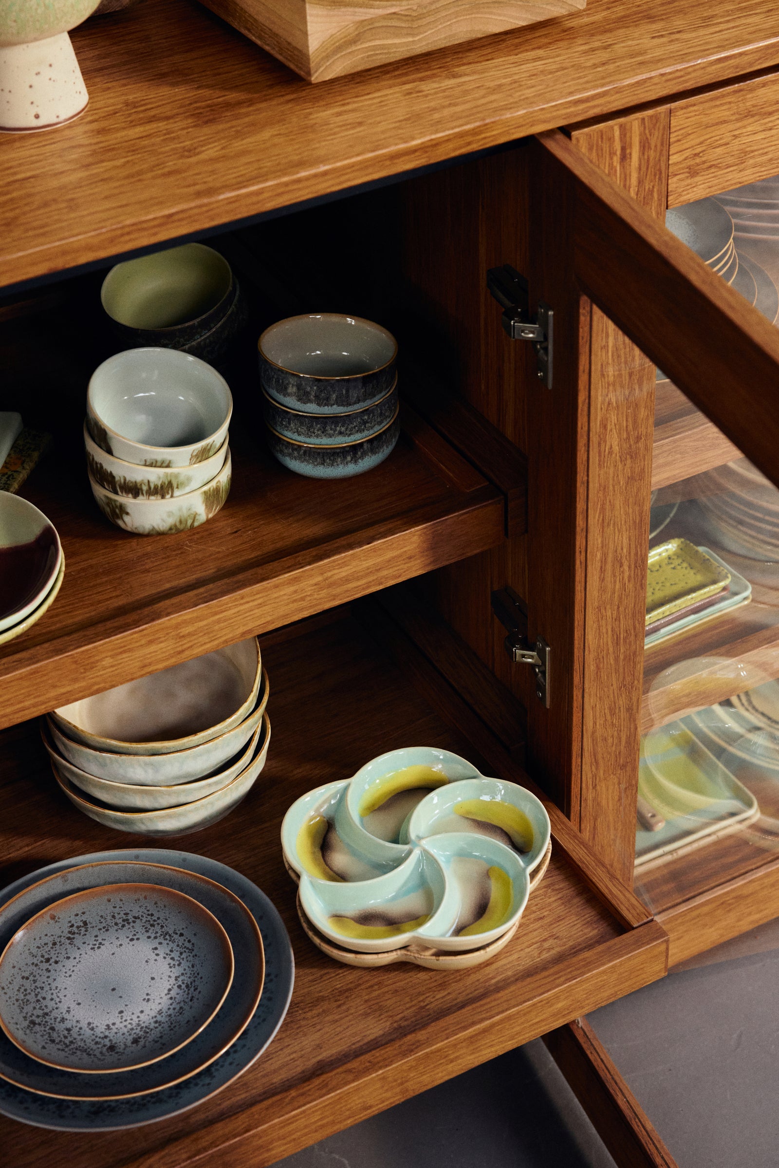 Wooden cabinet with shelves displaying various ceramic dishes and bowls.