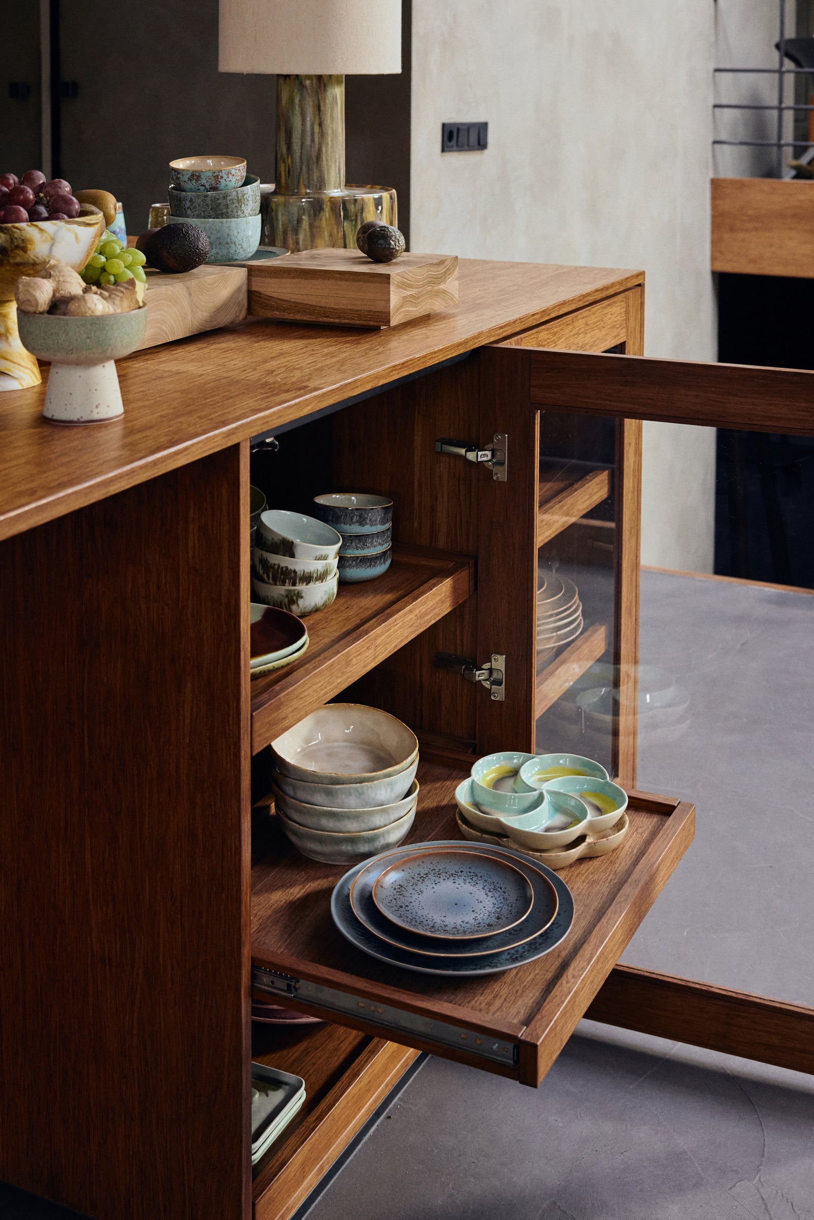 Wooden kitchen island with open cabinet displaying ceramic plates and bowls.