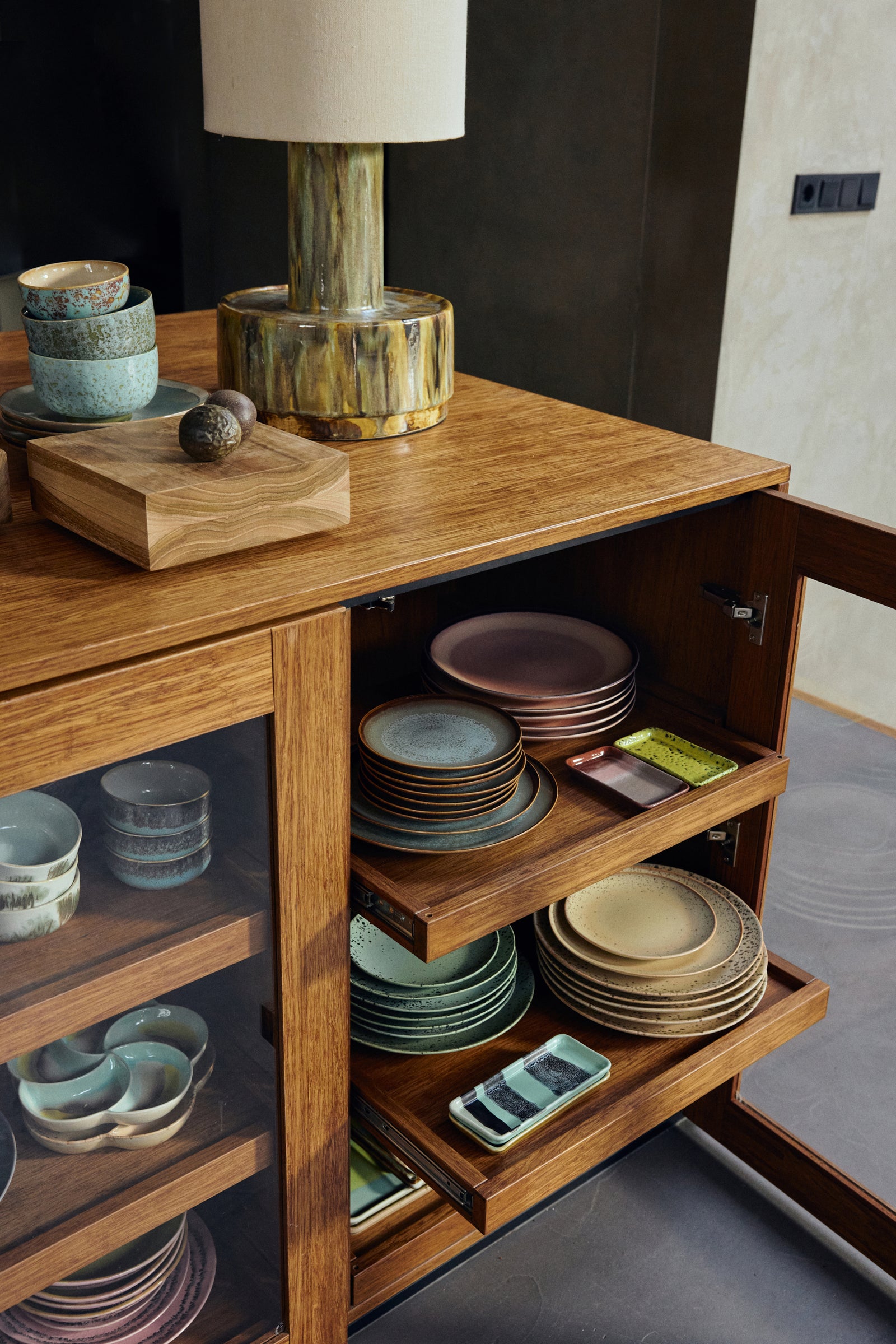 Wooden cabinet with ceramic plates and bowls on a dark background