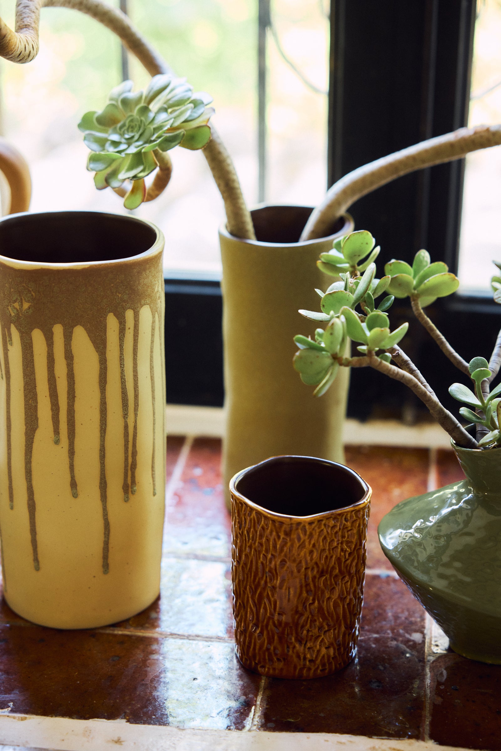 Three handmade ceramic vases with textured and dripple designs, styled with succulents on a tiled windowsill.