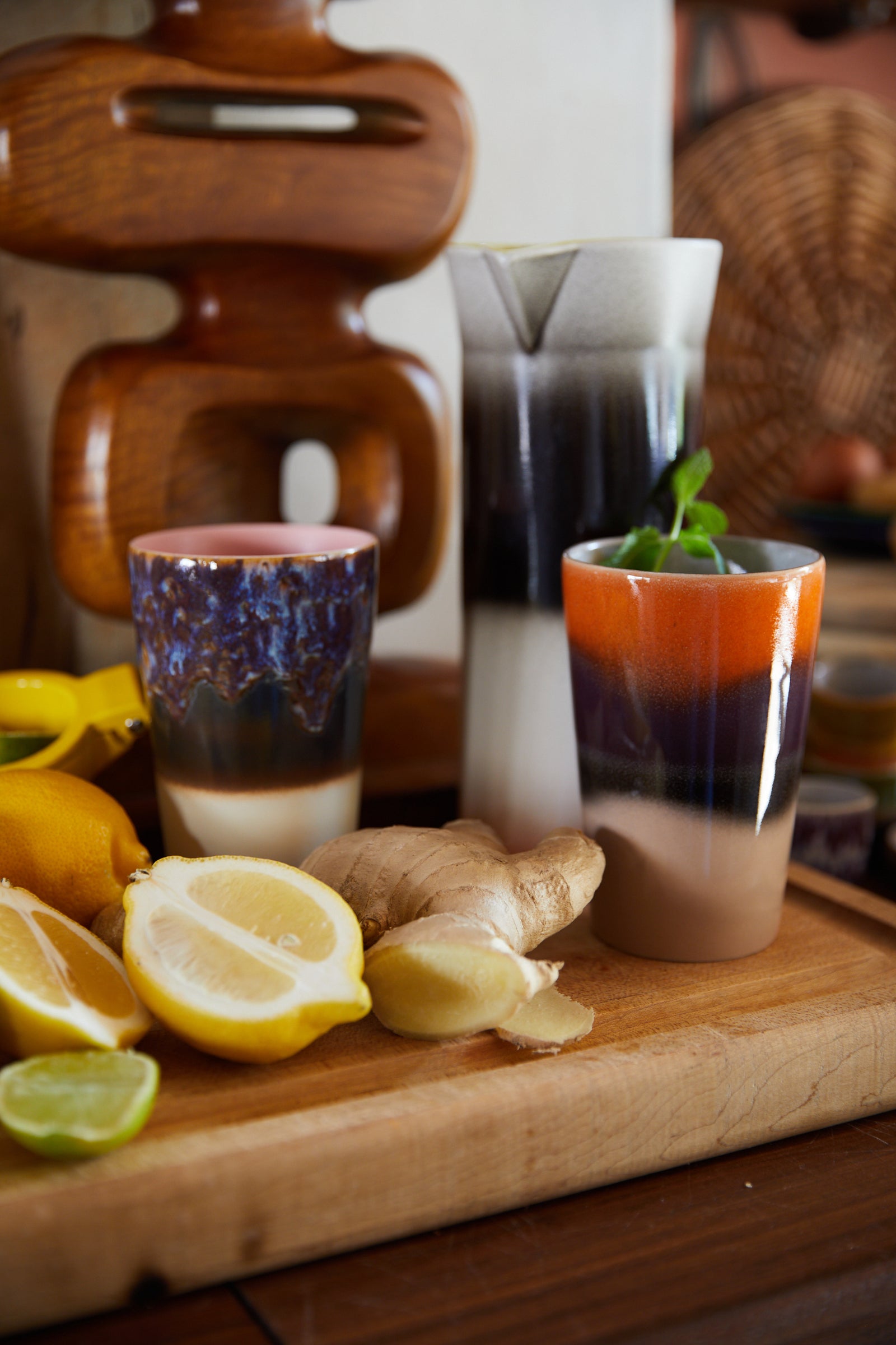 Two layered drinks in glasses on a wooden cutting board with lemons and ginger.