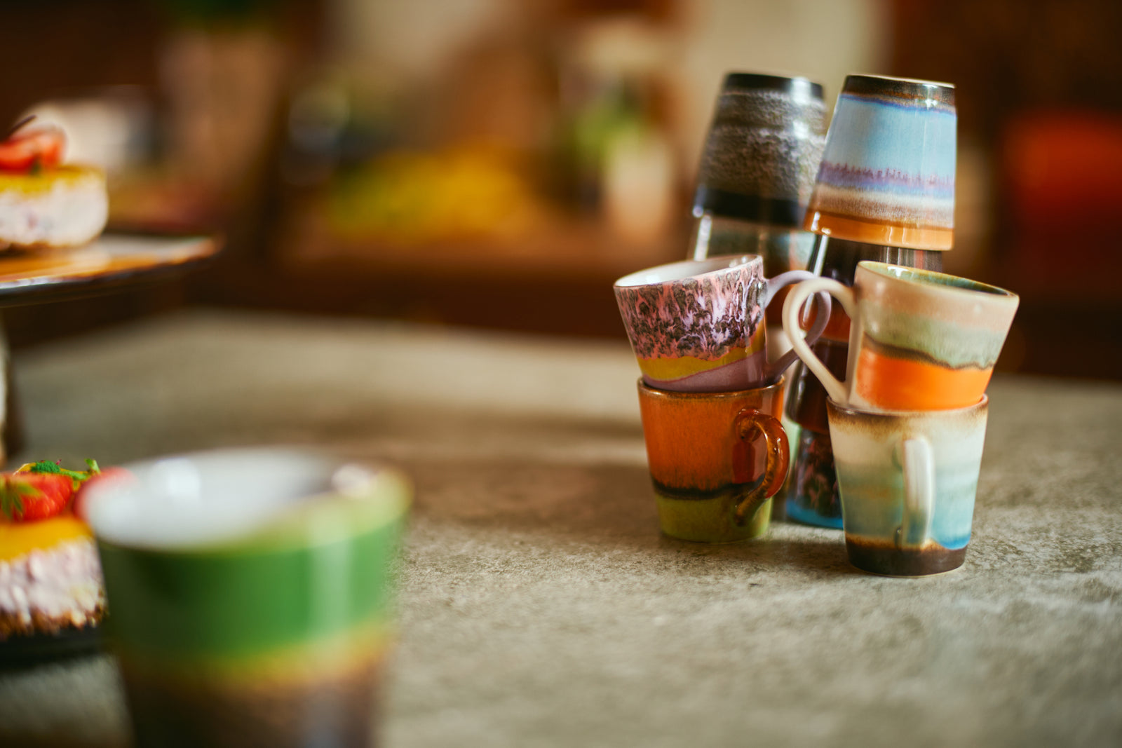 Colorful ceramic cups on a textured surface with blurred background