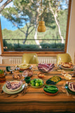 Dining table set with various dishes and a window view of greenery outside.