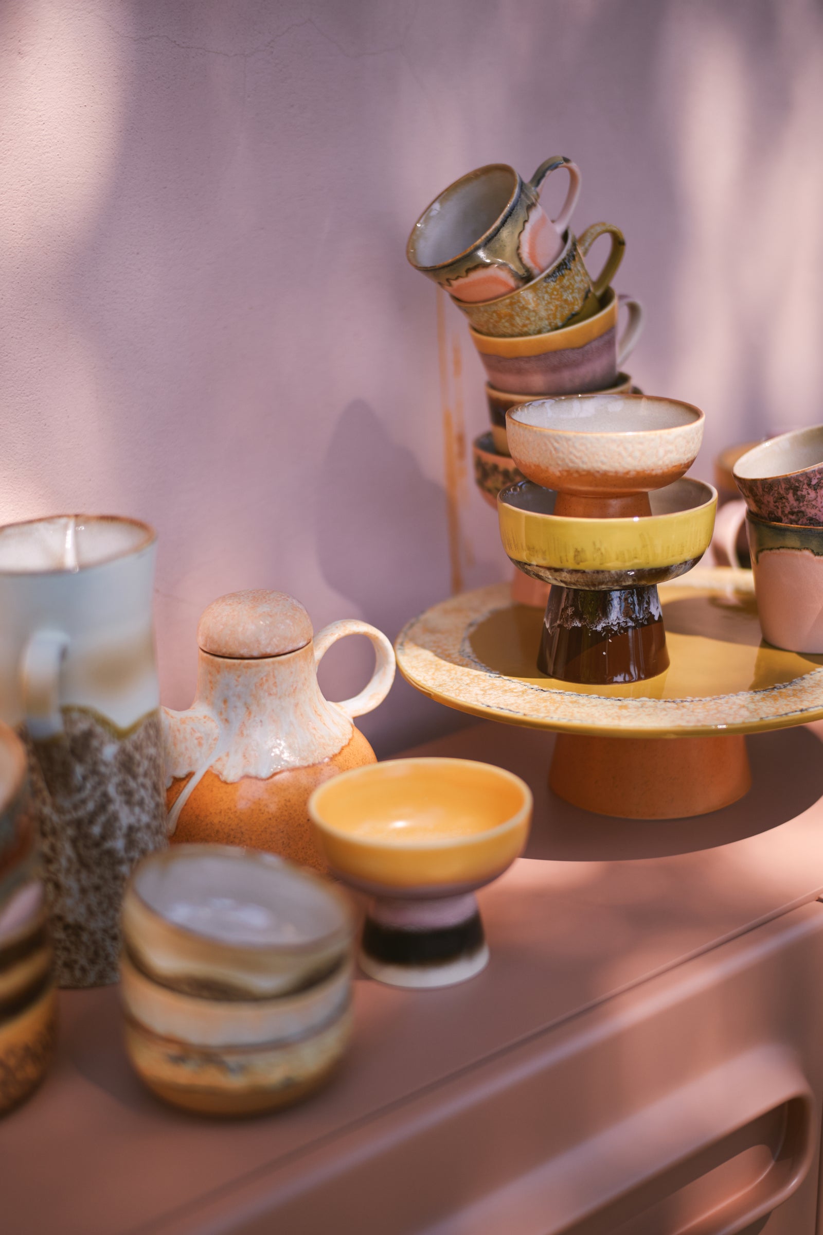 Stacked ceramic cups and bowls on a pink background