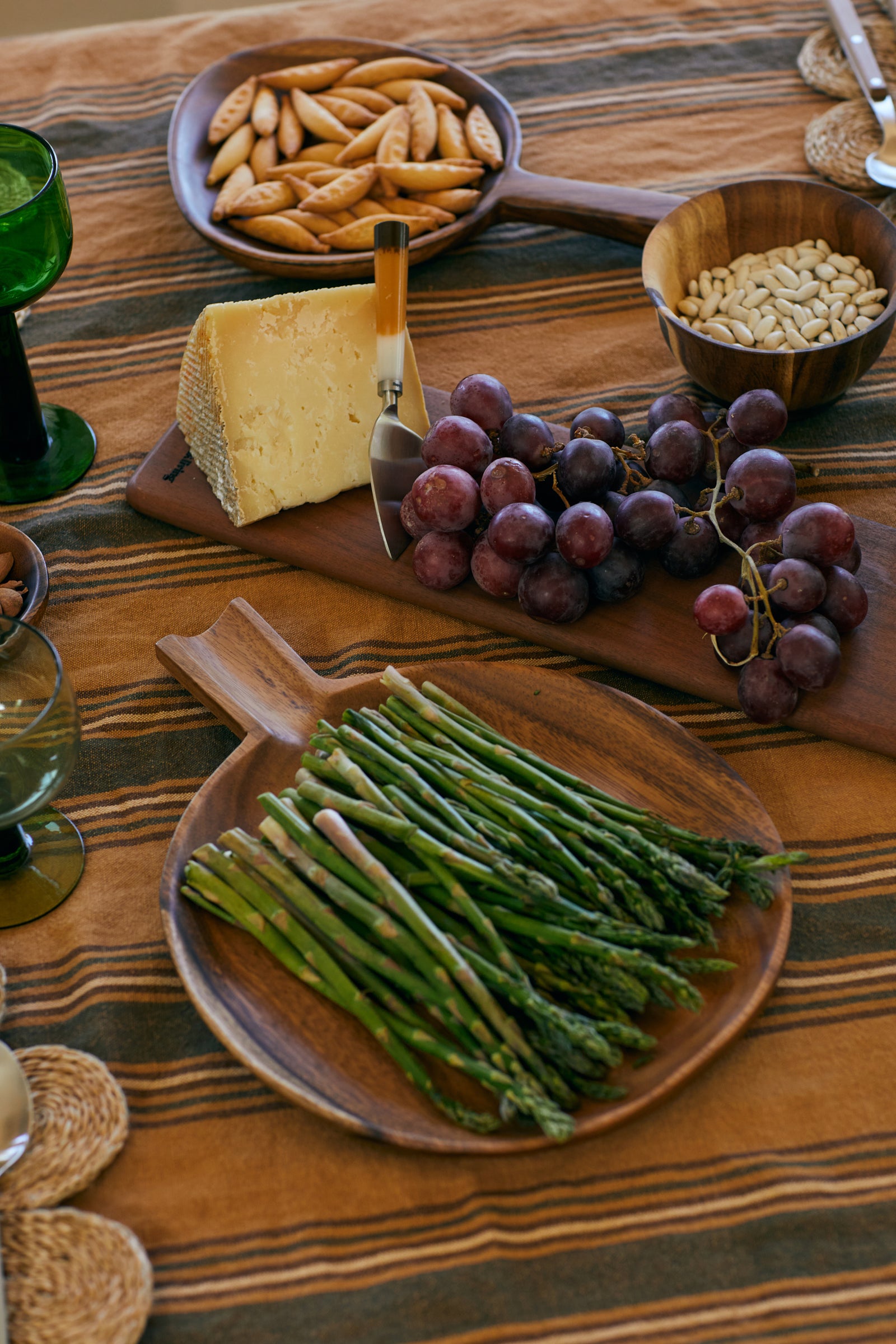 Assorted food items including asparagus, grapes, cheese, and crackers on a wooden table.