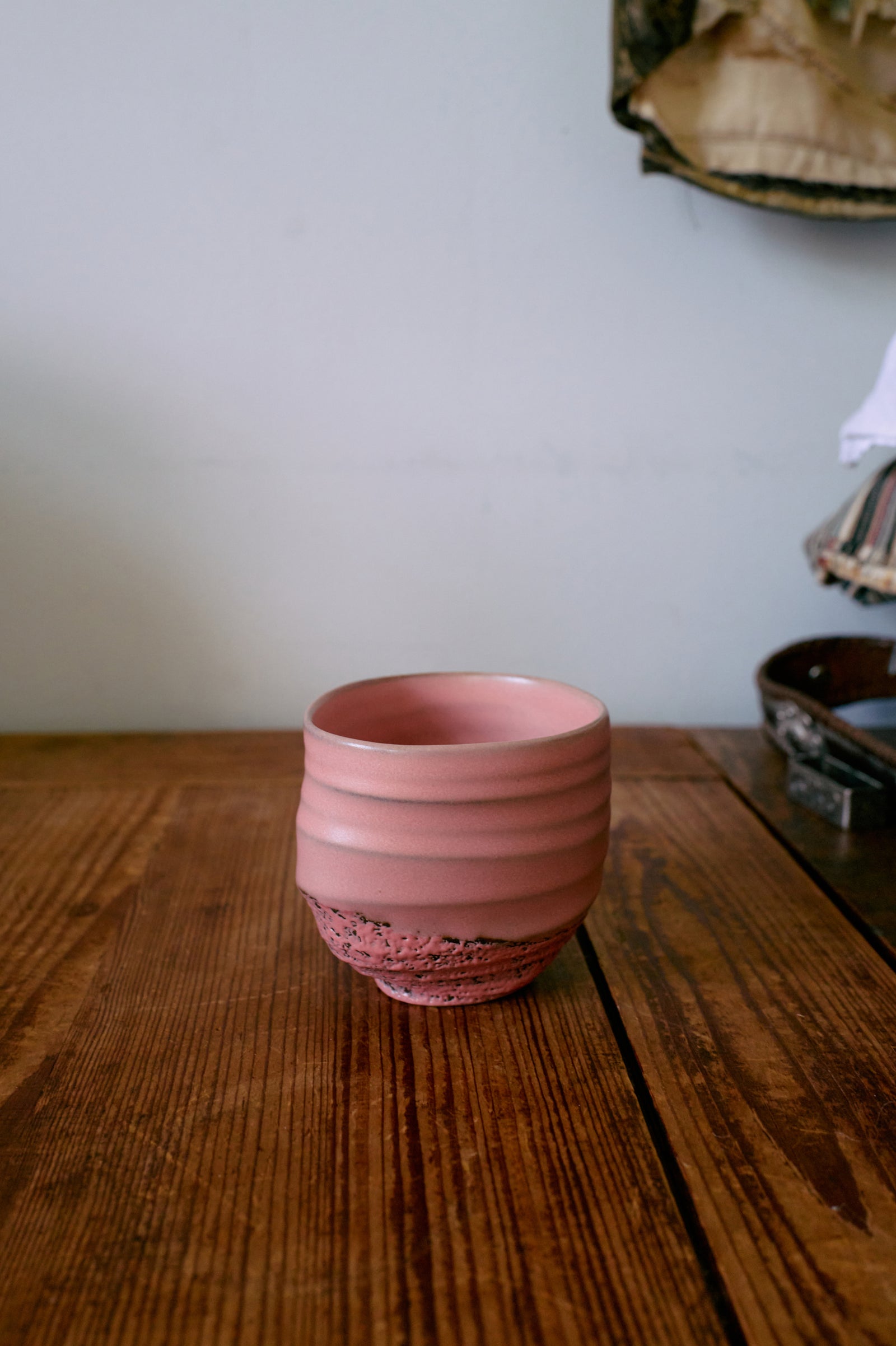 Pink ceramic cup on a wooden surface with a neutral background