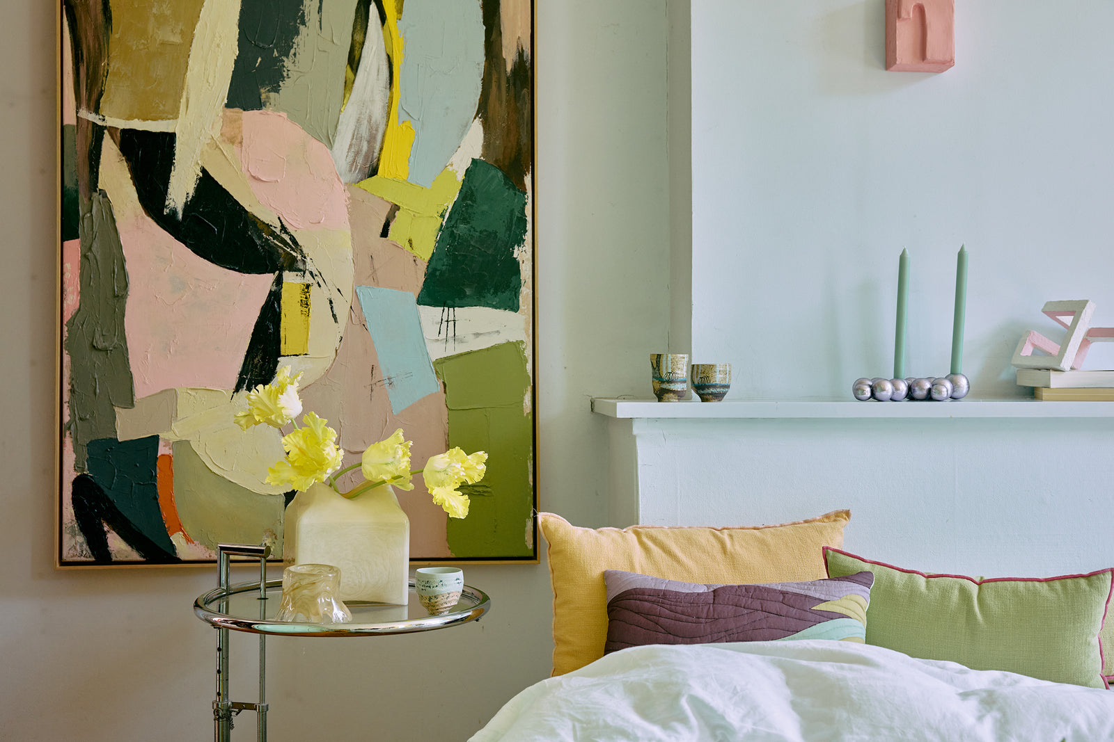 Room interior with abstract painting, floral arrangement, and colorful pillows.