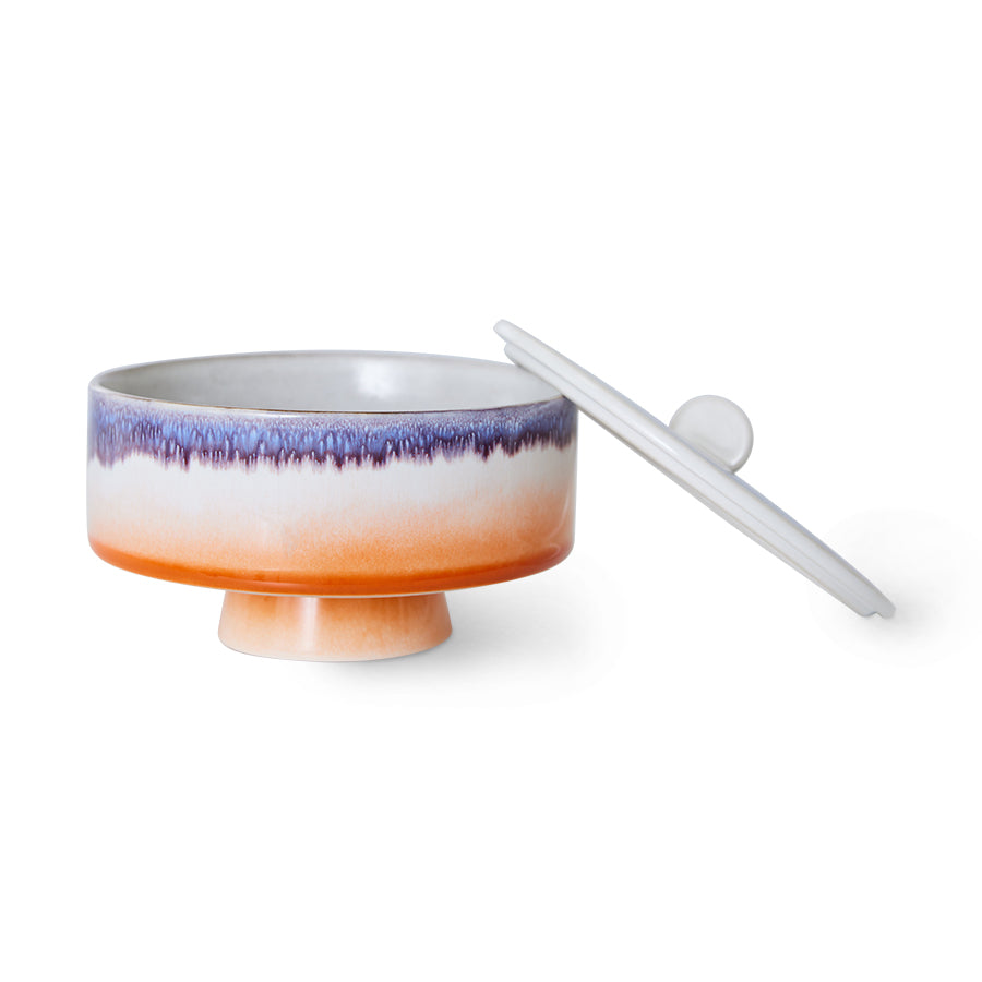 Ceramic footed bowl with gradient color design and a white lid on a white background