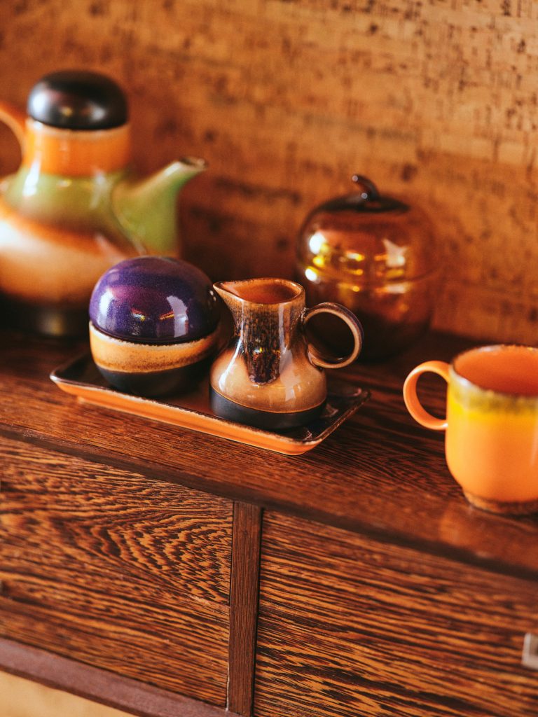 Wooden surface with ceramic items including a teapot, coffee pot, and cups.