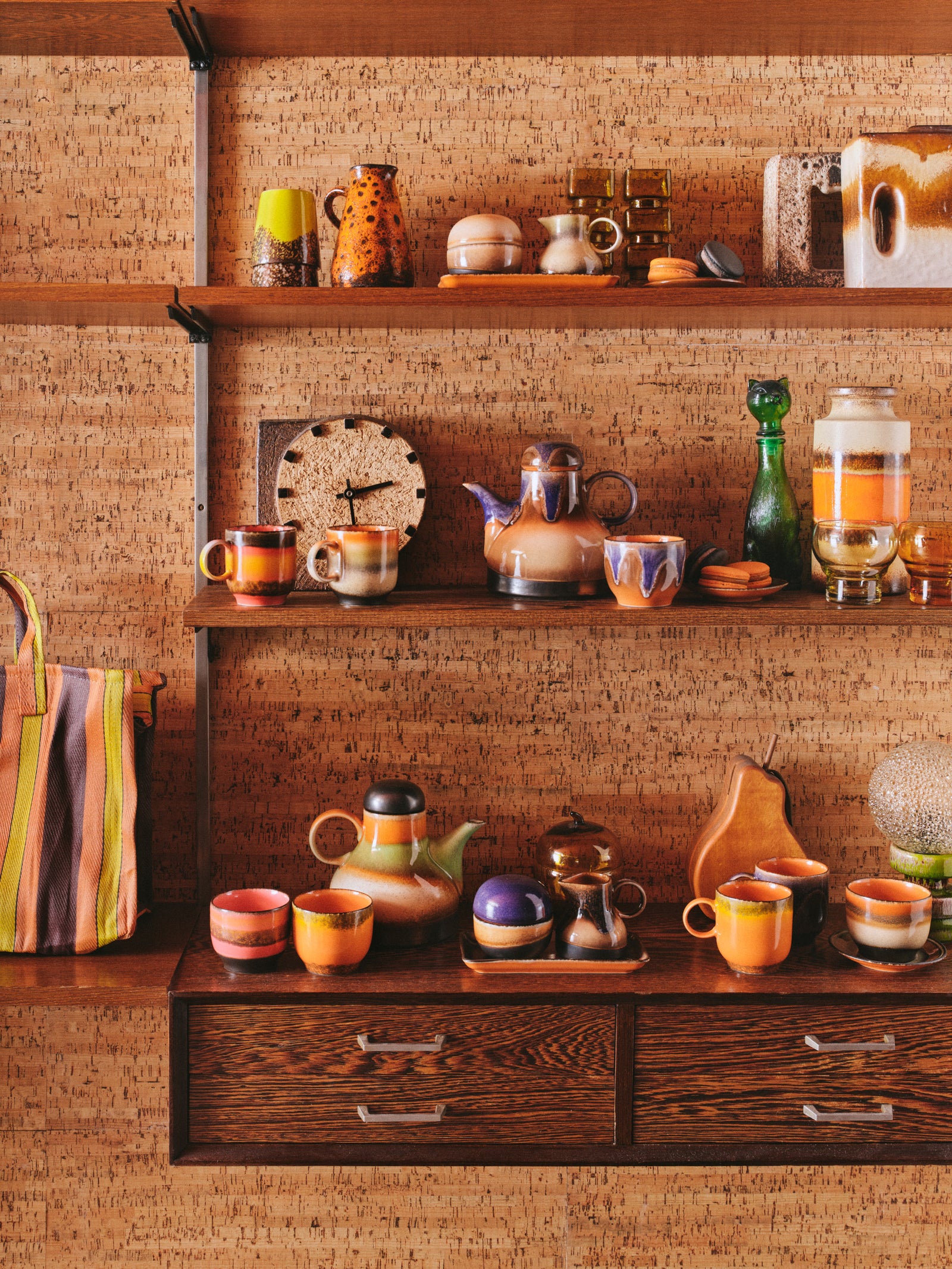 Wooden shelves with ceramic items against a cork wall.