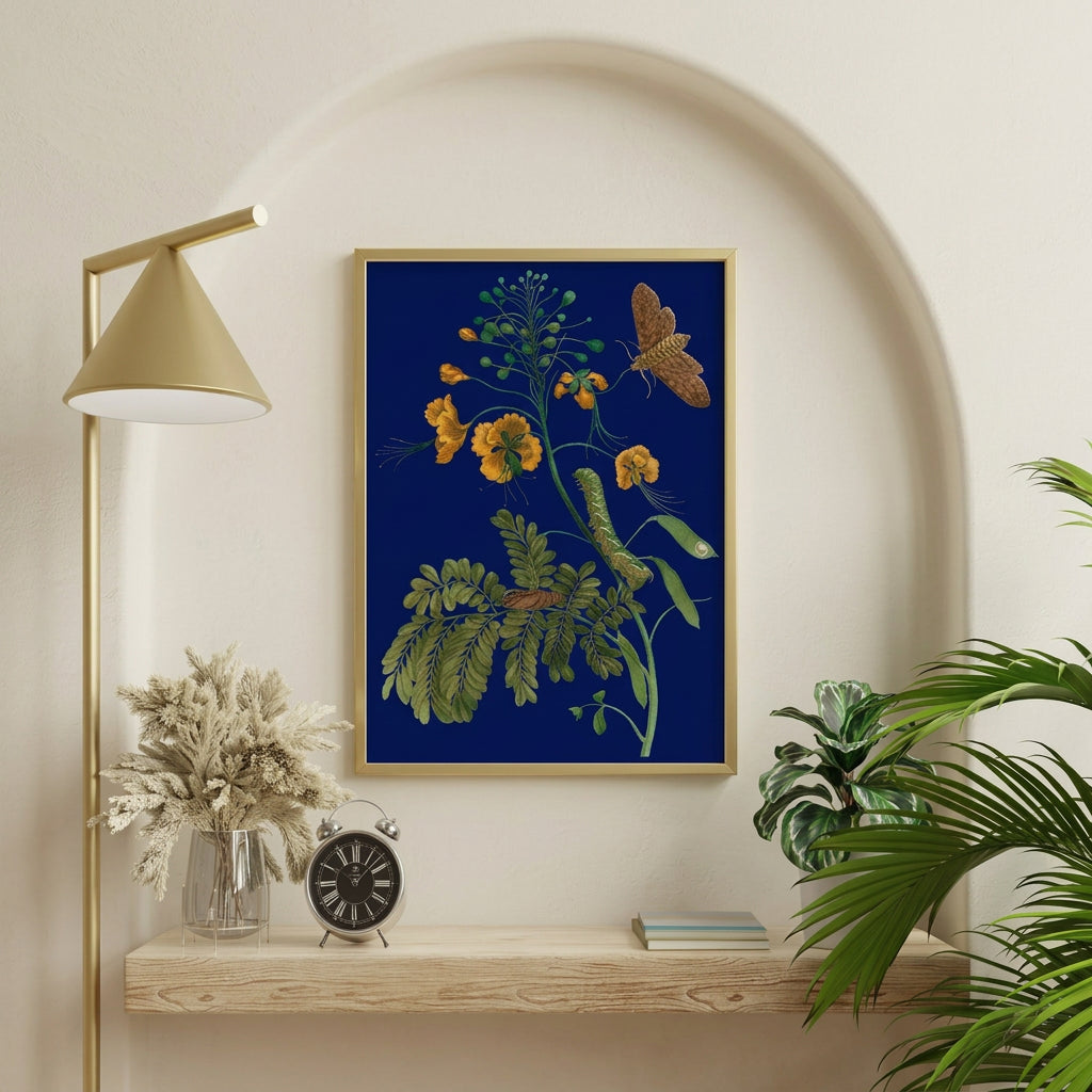 A framed botanical art print featuring yellow flowers, green leaves, and butterflies on a deep blue background, displayed on a wooden shelf in a styled room with a gold floor lamp, books, and a plant.