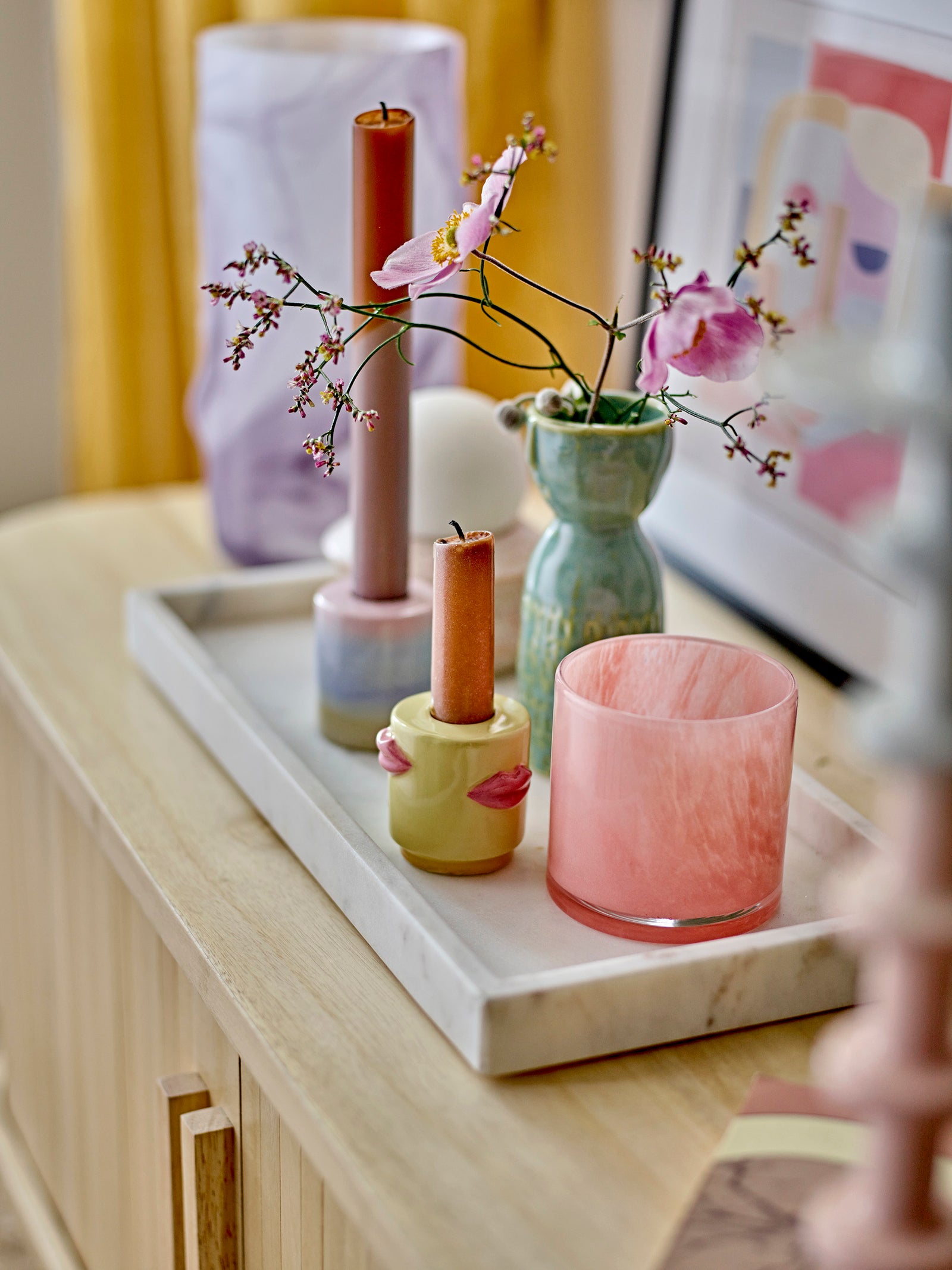 Decorative items including vases and candles on a marble tray with a blurred background