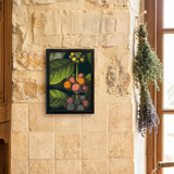 A framed botanical art print depicting green leaves and colorful cherries hangs on a rustic stone wall above a wooden counter with coffee beans, a mortar and pestle, and a French press in a warm kitchen setting.