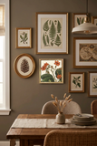 A framed botanical art print featuring orange flowers and green leaves on an off-white background, enclosed in an ornate gold-toned frame.