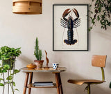 A framed lobster art print hangs on a beige wall in a styled room with a wooden chair, a small table, and several green houseplants.