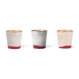 Three ceramic cups with speckled design and red base on a white background