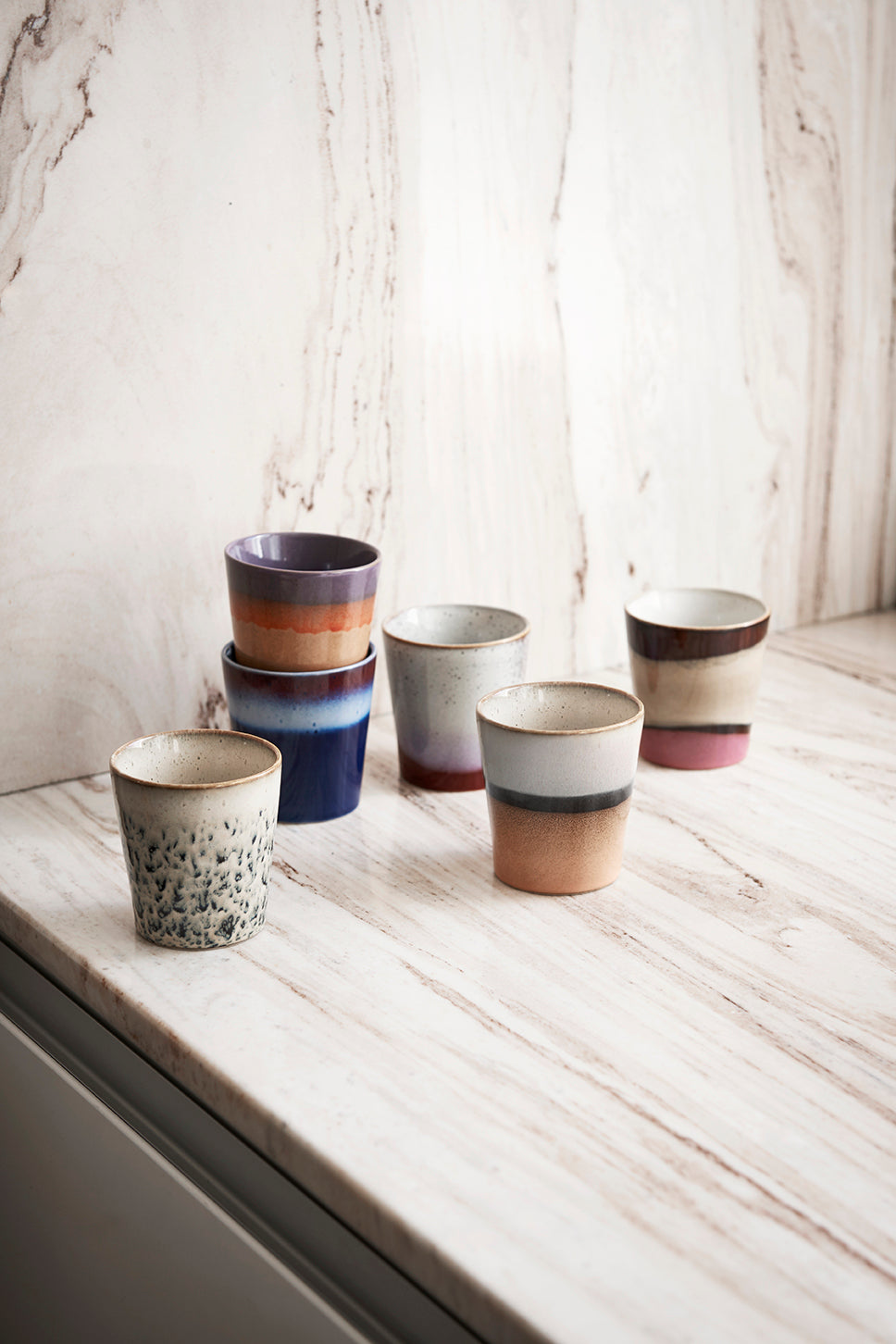 Set of ceramic cups with different designs on a wooden surface.