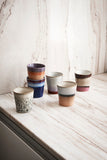 Set of ceramic cups with different designs on a wooden surface.