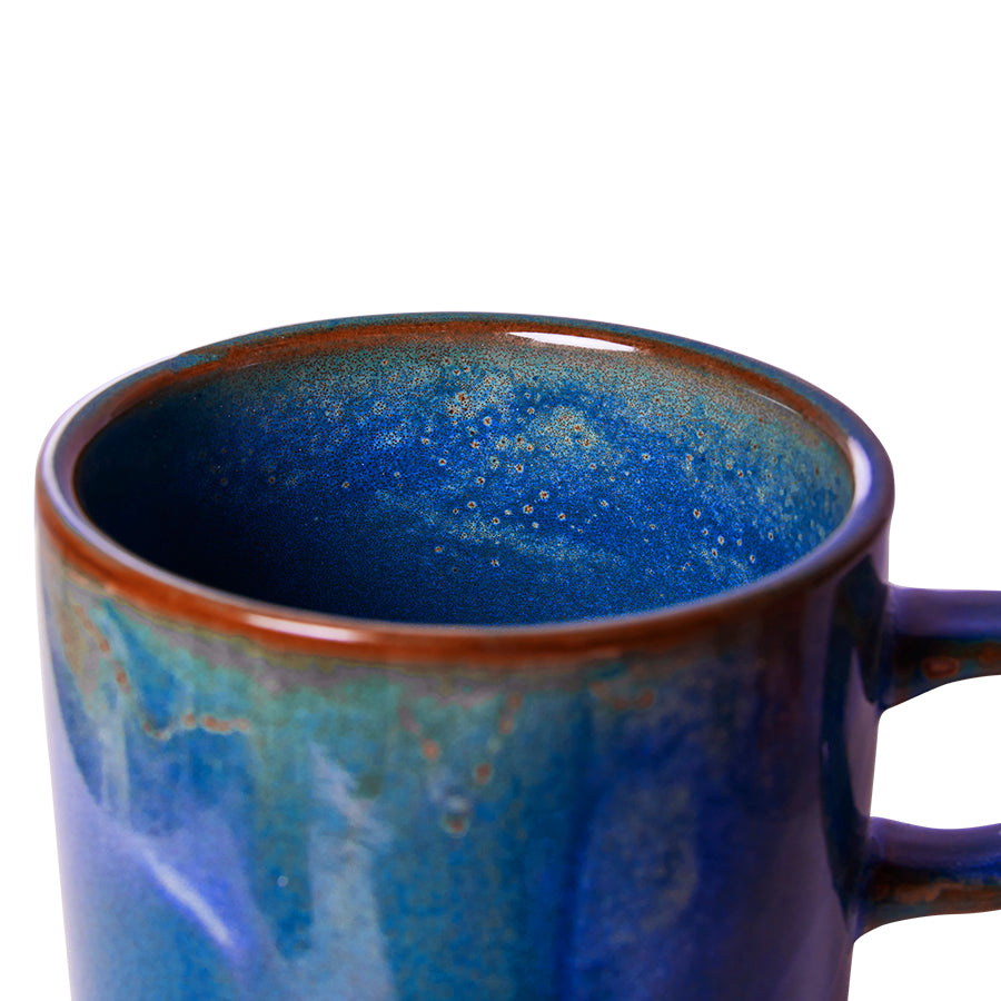 Blue ceramic mug with speckled interior on a white background