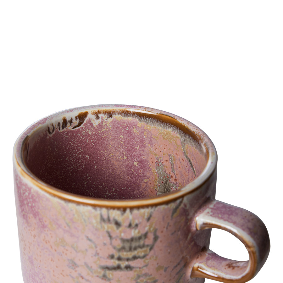 Ceramic mug with a textured surface filled with a dark liquid on a white background