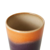 Ceramic cup with gradient color from brown to purple on a white background