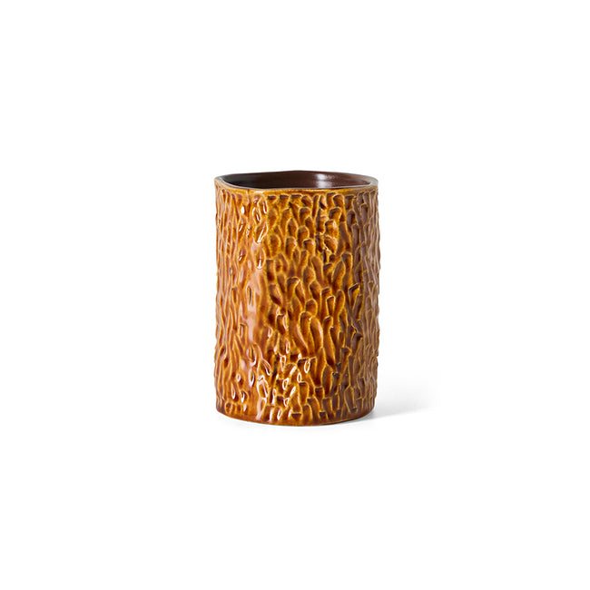 A cylindrical ceramic cup with a textured, bark-like glazed finish in warm brown and amber tones, set against a plain white background.