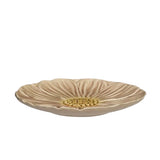 A shallow round ceramic dish shaped like a flower, featuring textured beige petals and a gold-colored center, shown against a plain white background.