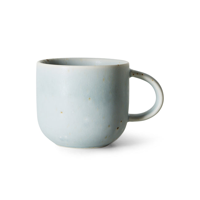 A light blue ceramic mug with a small, rounded handle and subtle speckled brown glaze details, shown on a clean white background.