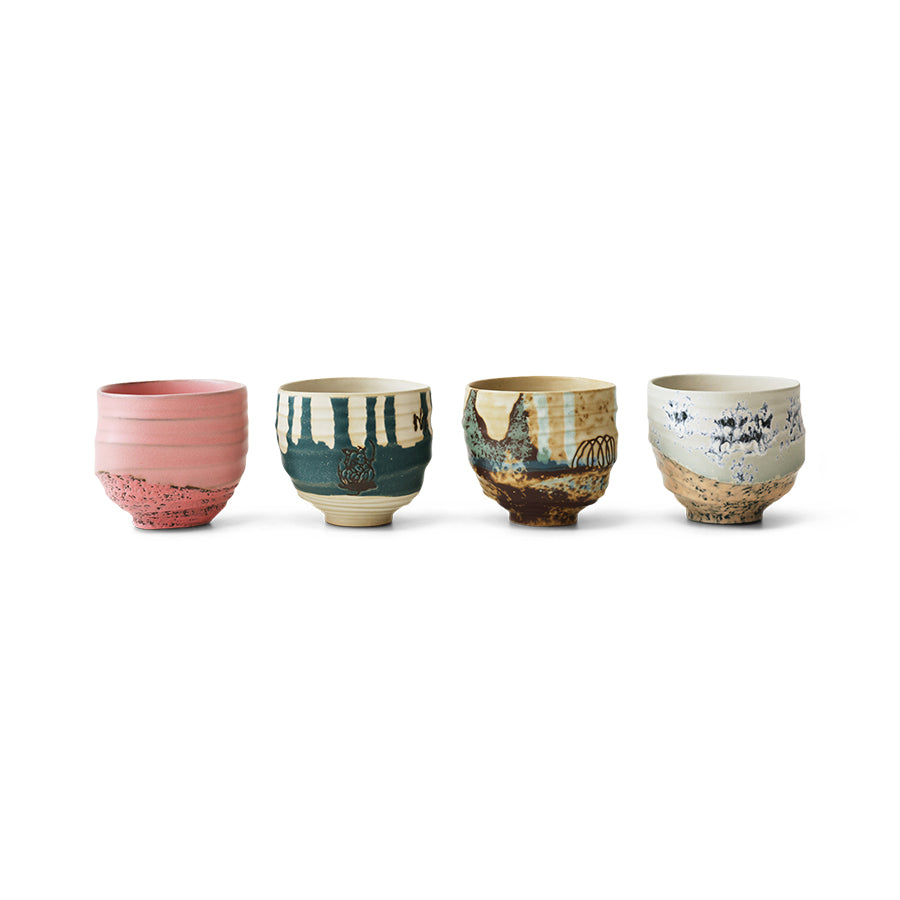 Set of four ceramic cups with unique designs on a white background