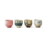 Set of four ceramic cups with unique designs on a white background