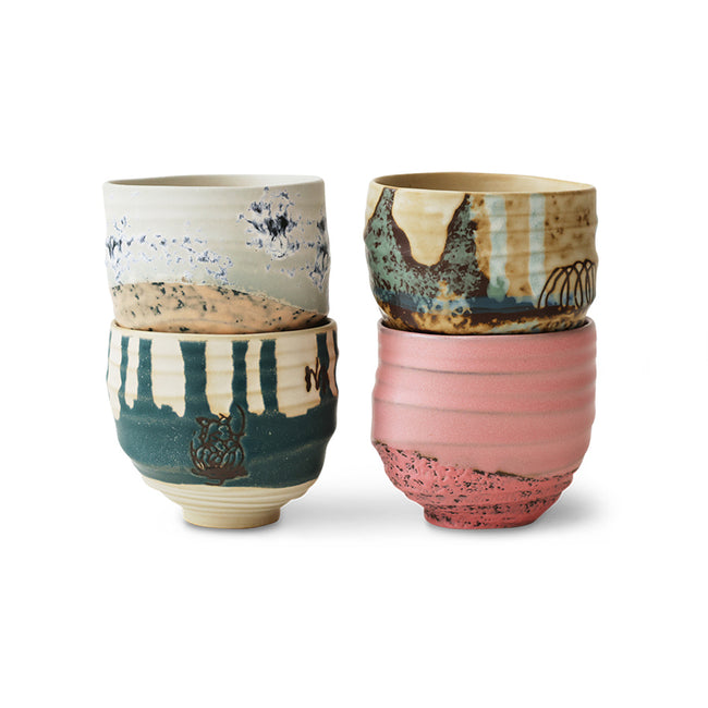 Set of four ceramic cups with unique patterns and colors on a white background