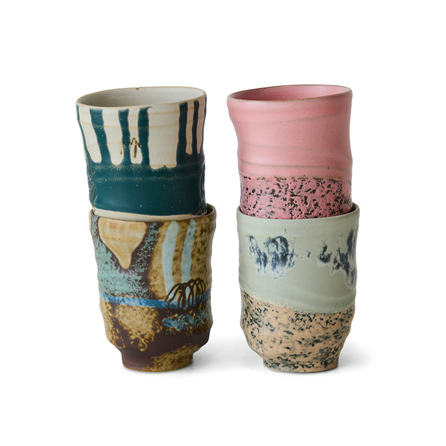 Set of four ceramic cups with unique patterns and colors on a white background
