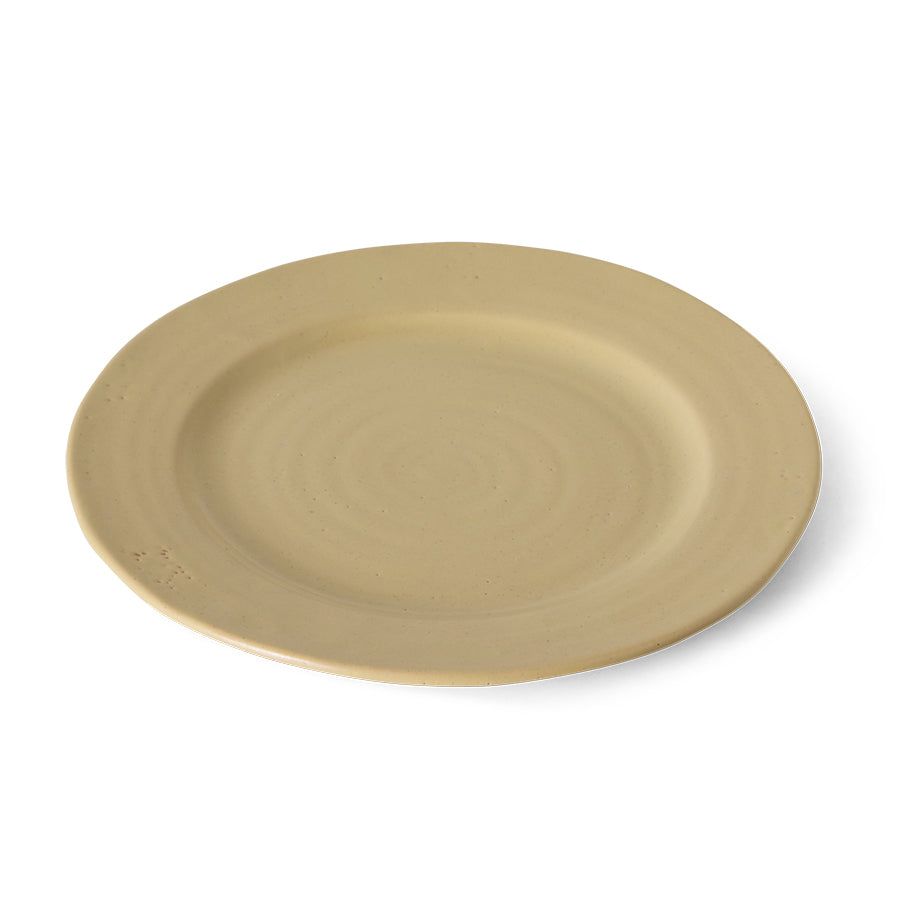 A round ceramic plate in a light beige color with subtle concentric ring textures, shown from a high-angle perspective on a white background.
