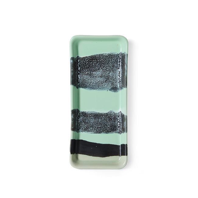 Rectangular glass tray with black and white striped design on a light green background