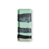 Rectangular glass tray with black and white striped design on a light green background