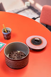 Ceramic pot with coffee beans on a red table